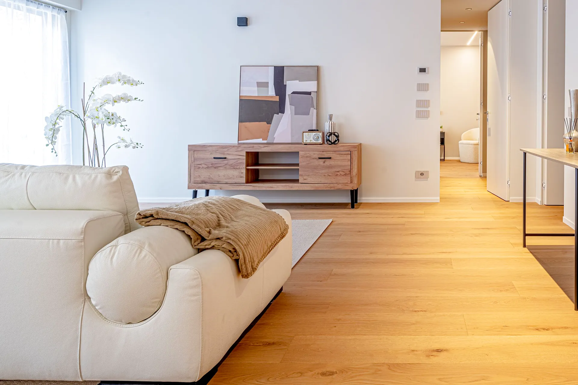 Living con divano chiaro, consolle in legno e ampio pavimento in rovere, valorizzato con home staging professionale